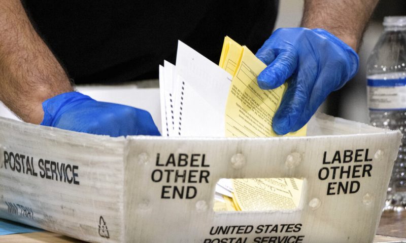 FILE - In this Jan. 5, 2021 file photo, Fulton County Georgia elections workers process absentee ballots for the Senate runoff election in Atlanta. When voters in Florida and Georgia request mailed ballots next year, they will have to make sure they do one more thing before sending it in: provide proof of identification. (AP Photo/Ben Gray, File)