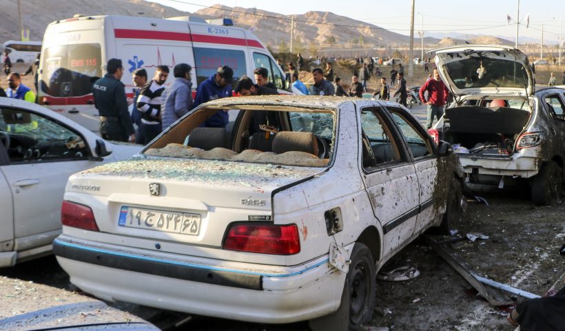 People stay next to destroyed cars after an explosion in Kerman, Iran, Wednesday, Jan. 3, 2024. Iran says bomb blasts at an event honoring a prominent Iranian general slain in a U.S. airstrike in 2020 have killed at least 103 people and wounded 188 others. (Tasnim News Agency via AP)