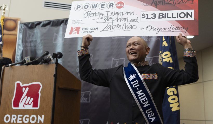 Cheng "Charlie" Saephan holds display check above his head after speaking during a news conference where it was revealed that he was one of the winners of the $1.3 billion Powerball jackpot at the Oregon Lottery headquarters on Monday, April 29, 2024, in Salem, Ore. (AP Photo/Jenny Kane)