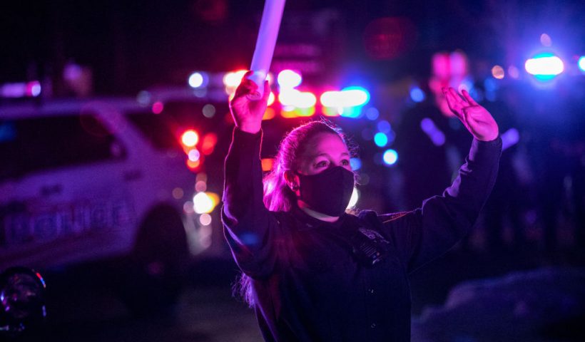 VALHALLA, NEW YORK - DECEMBER 21: Police officer Joyce Pagliuca waves to patients after her convoy of first responders arrived to a children's hospital as part of Operation Good Night Lights on December 21, 2020 in Valhalla, New York. Their lights flashing and sirens wailing, police, fire and EMS departments from throughout Westchester County convoyed to the Maria Fareri Children's Hospital at Westchester Medical Center to cheer up young patients and health workers there during the holidays. Due to the Covid-19 pandemic protocols, the police "Blue Santa" stayed outside, unable to enter the hospital and greet the children from close quarters. (Photo by John Moore/Getty Images)