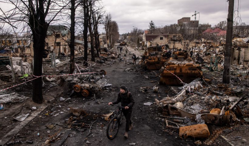 BUCHA, UKRAINE - APRIL 06: A man pushes his bike through debris and destroyed Russian military vehicles on a street on April 06, 2022 in Bucha, Ukraine. The Ukrainian government has accused Russian forces of committing a "deliberate massacre" as they occupied and eventually retreated from Bucha, 25km northwest of Kyiv. Hundreds of bodies have been found in the days since Ukrainian forces regained control of the town. (Photo by Chris McGrath/Getty Images)