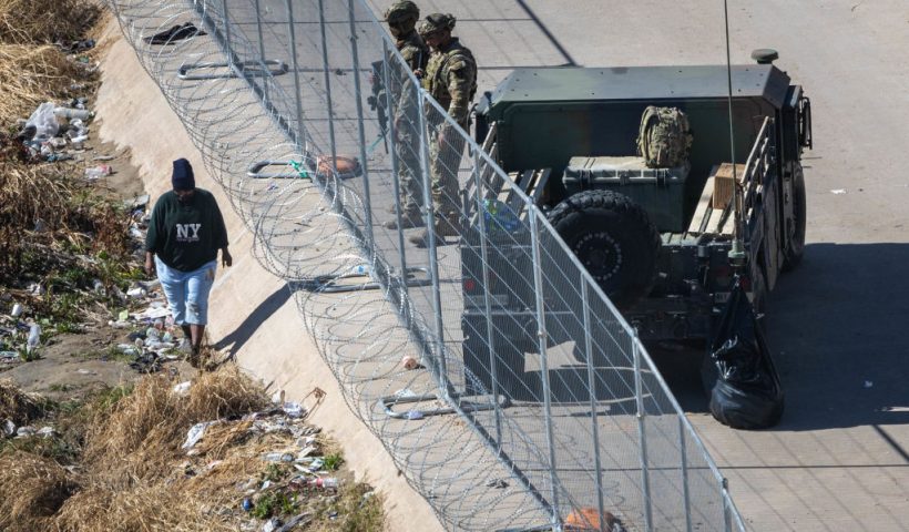 EL PASO, TEXAS - JANUARY 09: An immigrant passes Texas National Guard soldiers at the U.S.Mexico border on January 09, 2023 in El Paso, Texas. President Joe Biden visited El Paso the day prior, his first visit to the border since he became president two years before. His trip came just days after the administration changed U.S. asylum policy, making it easier to quickly expel more migrants at the border into Mexico. U.S. border authorities took into custody more than 2.5 million migrants in 2022, the highest number on record. (Photo by John Moore/Getty Images)