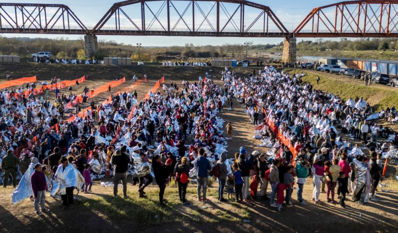 EAGLE PASS, TEXAS - DECEMBER 19: In an aerial view, thousands of immigrants, most wearing thermal blankets, await processing at a U.S. Border Patrol transit center on December 19, 2023 in Eagle Pass, Texas. Major surges of migrants illegally crossing the Rio Grande have overwhelmed U.S. border authorities in recent weeks. (Photo by John Moore/Getty Images)