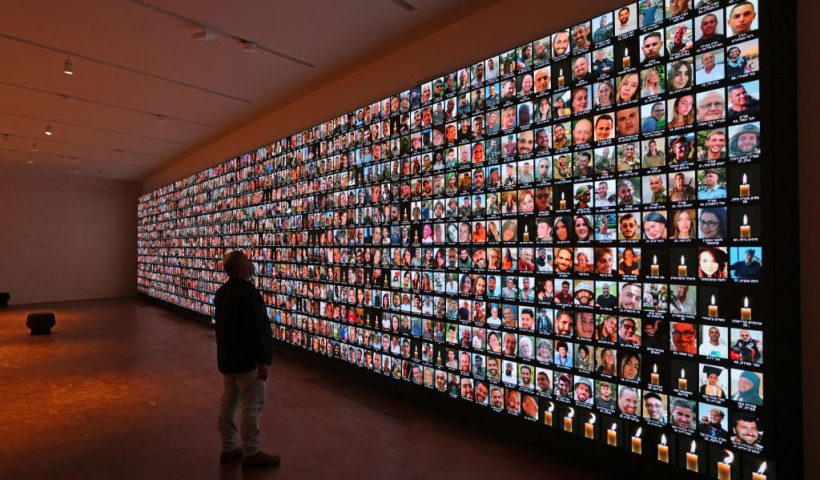 TOPSHOT - A visitor looks at a giant backlight screen bearing the portraits of the Israeli people who were killed during the October 7 attacks by Hamas in southern Israel or those who died during the ongoing battles between Israel and the Palestinian militant group Hamas in Gaza, at the National Library in Jerusalem, on January 25, 2024. (Photo by AHMAD GHARABLI / AFP) (Photo by AHMAD GHARABLI/AFP via Getty Images)