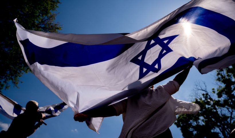 WASHINGTON, DC - MAY 2: Michal Rokah of Falls Church, Virginia (C) and Israeli Matan Showstack of Washington, DC (L) dance and wave large Israeli flags during a rally against campus antisemitism at George Washington University on May 2, 2024 in Washington, DC. A pro-Palestinian rally was also held at the school today, as protestors at college campuses around the country call for schools to divest from Israeli interests amid the ongoing war in Gaza. (Photo by Andrew Harnik/Getty Images)