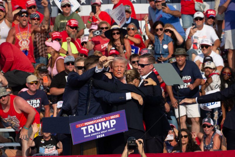 Republican candidate Donald Trump is seen with blood on his face surrounded by secret service agents as he is taken off the stage at a campaign event at Butler Farm Show Inc. in Butler, Pennsylvania, July 13, 2024. The suspected shooter who wounded Republican presidential candidate Donald Trump at a rally is dead, US media reported Saturday, along with one bystander. (Photo by Rebecca DROKE / AFP) (Photo by REBECCA DROKE/AFP via Getty Images)