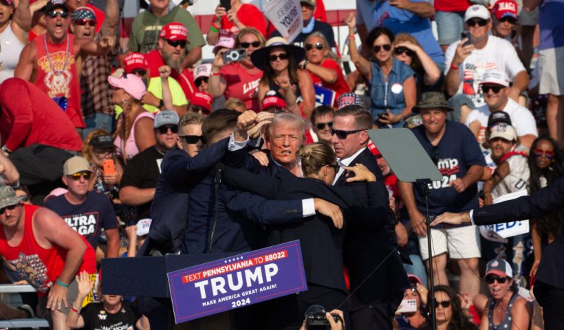 Republican candidate Donald Trump is seen with blood on his face surrounded by secret service agents as he is taken off the stage at a campaign event at Butler Farm Show Inc. in Butler, Pennsylvania, July 13, 2024. The suspected shooter who wounded Republican presidential candidate Donald Trump at a rally is dead, US media reported Saturday, along with one bystander. (Photo by Rebecca DROKE / AFP) (Photo by REBECCA DROKE/AFP via Getty Images)