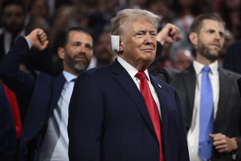 US former President and 2024 Republican presidential candidate Donald Trump looks on as his sons Donald Trump Jr. and Eric Trump gesture behind him during the first day of the 2024 Republican National Convention at the Fiserv Forum in Milwaukee, Wisconsin, July 15, 2024. Donald Trump won formal nomination as the Republican presidential candidate and picked a right-wing loyalist for running mate, kicking off a triumphalist party convention in the wake of last weekend's failed assassination attempt. (Photo by Brendan SMIALOWSKI / AFP) (Photo by BRENDAN SMIALOWSKI/AFP via Getty Images)