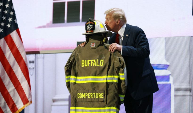 MILWAUKEE, WISCONSIN - JULY 18: Republican presidential nominee, former U.S. President Donald Trump embraces the firefighter uniform of Corey Comperatore as he speaks on stage on the fourth day of the Republican National Convention at the Fiserv Forum on July 18, 2024 in Milwaukee, Wisconsin. Delegates, politicians, and the Republican faithful are in Milwaukee for the annual convention, concluding with former President Donald Trump accepting his party's presidential nomination. The RNC takes place from July 15-18. (Photo by Joe Raedle/Getty Images)