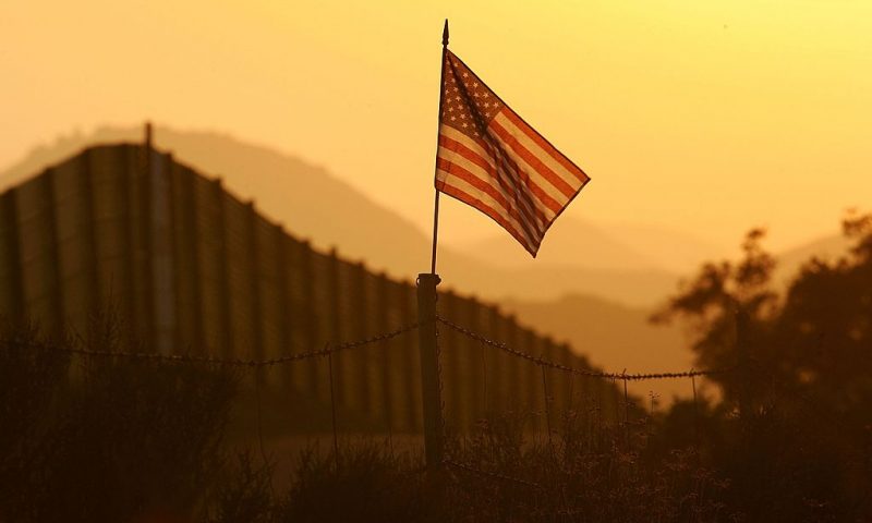 CAMPO, CA - OCTOBER 08: A U.S. flag put up by activists who oppose illegal immigration flies near the US-Mexico border fence in an area where they search for border crossers October 8, 2006 near Campo, California. The activists want the fence expanded into a fully-lit double-fenced barrier between the US (R) and Mexico. US Fish and Wildlife Service wardens and environmentalists warn that a proposed plan by US lawmakers to construct 700 miles of double fencing along the 2,000-mile US-Mexico border, in an attempt to wall-out illegal immigrants, would also harm rare wildlife. Wildlife experts say cactus-pollinating insects would fly around fence lights, birds that migrate by starlight in the desert wilderness would be confused, and large mammals such as jaguars, Mexican wolves, Sonoran pronghorn antelope, and desert bighorn sheep would be blocked from migrating across the international border, from California to Texas. (Photo by David McNew/Getty Images)