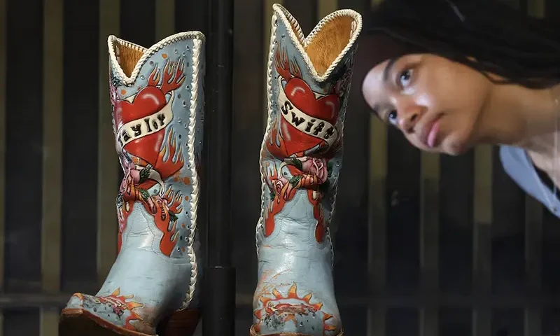 Employee Saffron poses as she views cowboy boots worn and loaned by Taylor Swift, which form part of the Taylor Swift Songbook Trail exhibition celebrating the work of the music artist at the V&A Museum in London, Britain, July 24, 2024. REUTERS/Toby Melville