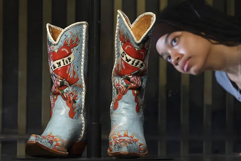 Employee Saffron poses as she views cowboy boots worn and loaned by Taylor Swift, which form part of the Taylor Swift Songbook Trail exhibition celebrating the work of the music artist at the V&A Museum in London, Britain, July 24, 2024. REUTERS/Toby Melville