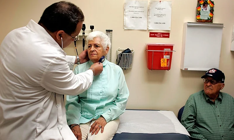 Dr. Ausberto Bianchi checks Ofelia Perez during an exam at the CAC-Florida medical center March 22, 2007 in Miami, Florida. Her husband Disnardo Perez watches. The center, formerly the Clinica Asociacion Cubana and now owned by Humana, provides seniors with regular primary care physicians and access to specialists several times a week. The center, emphasizing its Cuban approach, provides a place not only where health care is provided, but a kind of meeting place for the community where patients can be found playing card games, exercising, enjoying refreshments and participating in bingo tournaments and other events. (Photo by Joe Raedle/Getty Images)