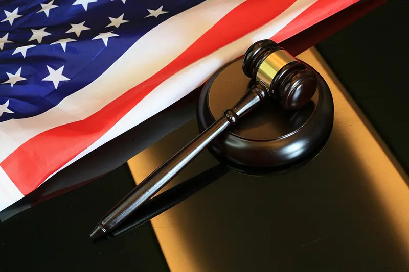 Image of a gavel lying next to an American flag. Photo by sergeitokmakov.