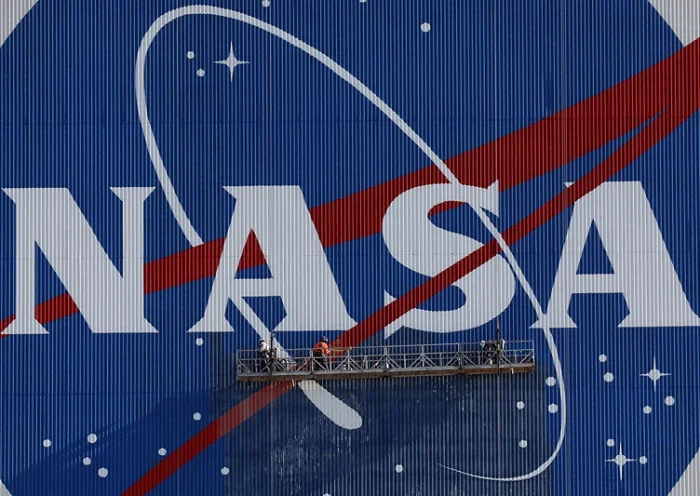 Painters refurbish the NASA logo on the Vehicle Assembly Building at the Kennedy Space Center in Florida in Florida on May 29, 2020. The faded 10-story-tall insignia was last painted 13 years ago. The SpaceX Falcon 9 rocket with the Crew Dragon capsule is rescheduled to launch to the International Space Station on May 30, carrying astronauts Bob Behnken and Doug Hurley. (Photo by Gregg Newton / AFP) (Photo by GREGG NEWTON/AFP via Getty Images)