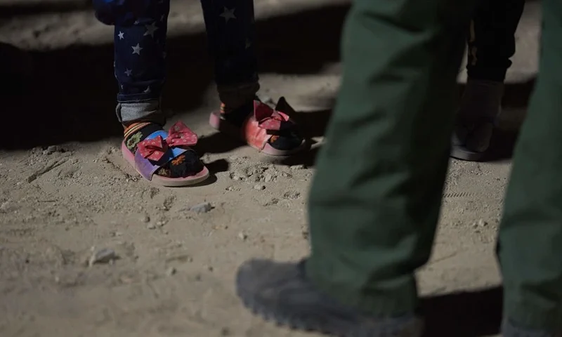 TOPSHOT - A girl (detail shoes) waits to be processed by US Border Patrol agent (detail shoe) after illegally crossing the US-Mexico border in Yuma, Arizona in the early morning of July 11, 2022. - Every year, tens of thousands of migrants fleeing violence or poverty in Central and South America attempt to cross the border into the United States in pursuit of the American dream. Many never make it. (Photo by allison dinner / AFP) (Photo by ALLISON DINNER/AFP via Getty Images)