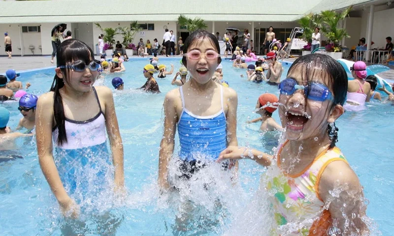 Elementary school children splash water in a swimming pool at Tokyo's Shin-Takanawa Prince Hotel on June 20, 2009 as the hotel opens its outdoor swimming pool for the season. Tokyo's temperature is expected to climb near 30-degree Celsius at a break of the rainy season. AFP PHOTO/Yoshikazu TSUNO (Photo by AFP) (Photo by -/AFP via Getty Images)