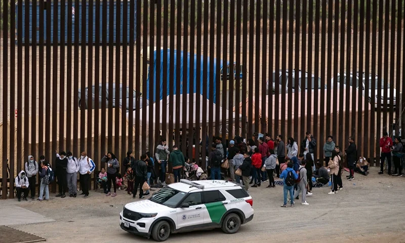 Migrants and asylum seekers wait to be processed by the Border Patrol between fences at the US-Mexico border seen from Tijuana, Baja California state, Mexico, on June 5, 2024. President Joe Biden said Tuesday he had ordered sweeping new migrant curbs to "gain control" of the US-Mexico border, making a dramatic bid to neutralize one of his political weak spots in his reelection battle against Donald Trump. (Photo by Guillermo Arias / AFP) (Photo by GUILLERMO ARIAS/AFP via Getty Images)