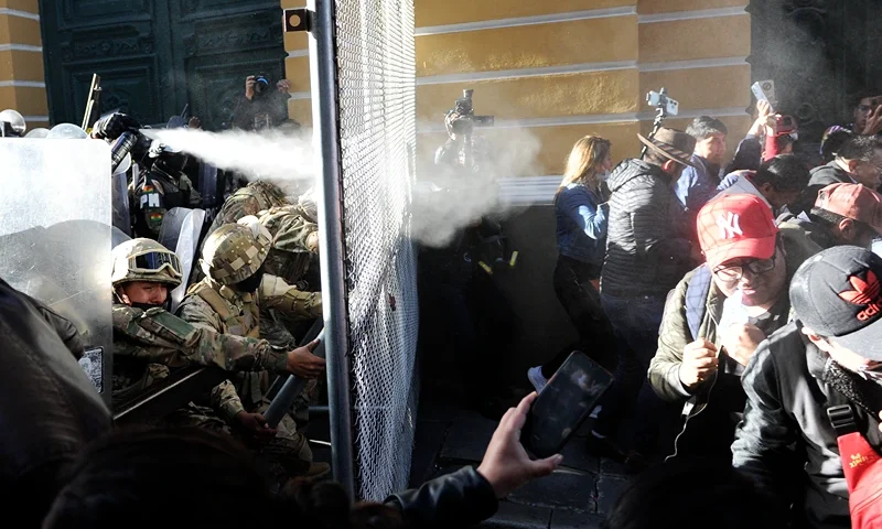 BOLIVIA-POLITICS-ARMY People take cover from tear gas fired by Military police at Plaza Murillo in La Paz on June 26, 2024. Bolivian President Luis Arce on Wednesday slammed an attempted "coup d'etat" after soldiers and tanks deployed outside government buildings and tried to knock down a door of the presidential palace, before pulling back. (Photo by JORGE BERNAL / AFP) (Photo by JORGE BERNAL/AFP via Getty Images)