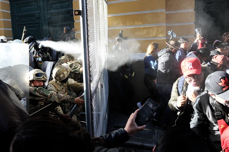 BOLIVIA-POLITICS-ARMY
People take cover from tear gas fired by Military police at Plaza Murillo in La Paz on June 26, 2024. Bolivian President Luis Arce on Wednesday slammed an attempted "coup d'etat" after soldiers and tanks deployed outside government buildings and tried to knock down a door of the presidential palace, before pulling back. (Photo by JORGE BERNAL / AFP) (Photo by JORGE BERNAL/AFP via Getty Images)