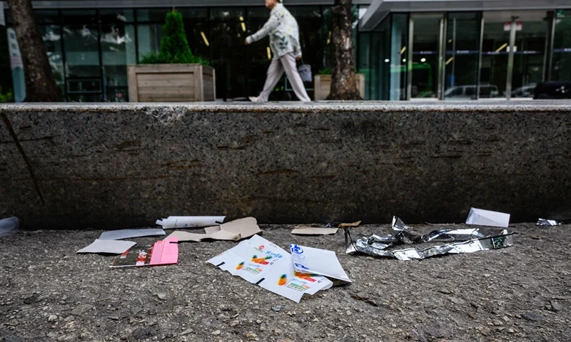 TOPSHOT-SKOREA-NKOREA-BALLOONS-POLITICS TOPSHOT - A pedestrian walks along a pavement past pieces of North Korean food packaging, sweet wrappers and paper suspected to be from trash balloons sent from North Korea, in Seoul on July 24, 2024. North Korean sweet wrappers and packets of crackers and other snacks made at a factory once visited by leader Kim Jong Un were found by AFP reporters on Seoul streets on July 24. (Photo by Anthony WALLACE / AFP) (Photo by ANTHONY WALLACE/AFP via Getty Images)