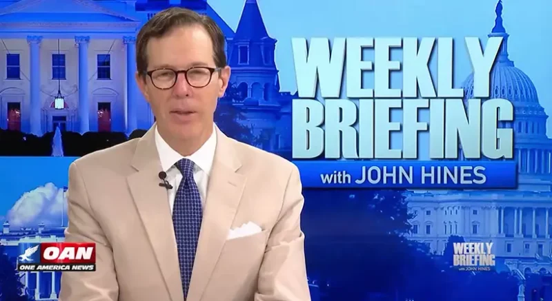 John Hines at the desk during Weekly Briefing