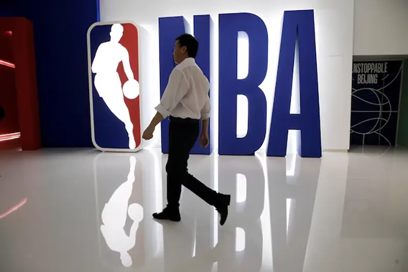 A man walks past an NBA logo at an NBA exhibition in Beijing, China October 8, 2019. REUTERS/Jason Lee/File Photo