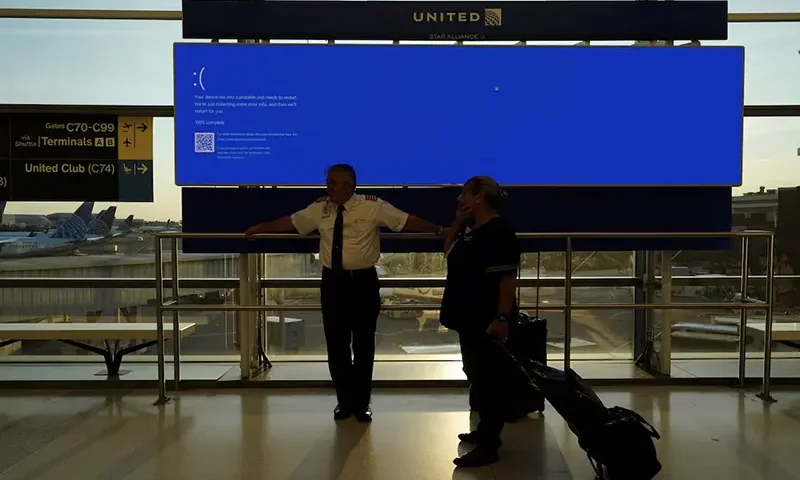 United Airlines employees wait by a departures monitor displaying a blue error screen, also known as the “Blue Screen of Death” inside Terminal C in Newark International Airport, after United Airlines and other airlines grounded flights due to a worldwide tech outage caused by an update to CrowdStrike's "Falcon Sensor" software which crashed Microsoft Windows systems, in Newark, New Jersey, U.S., July 19, 2024. REUTERS/Bing Guan/File Photo