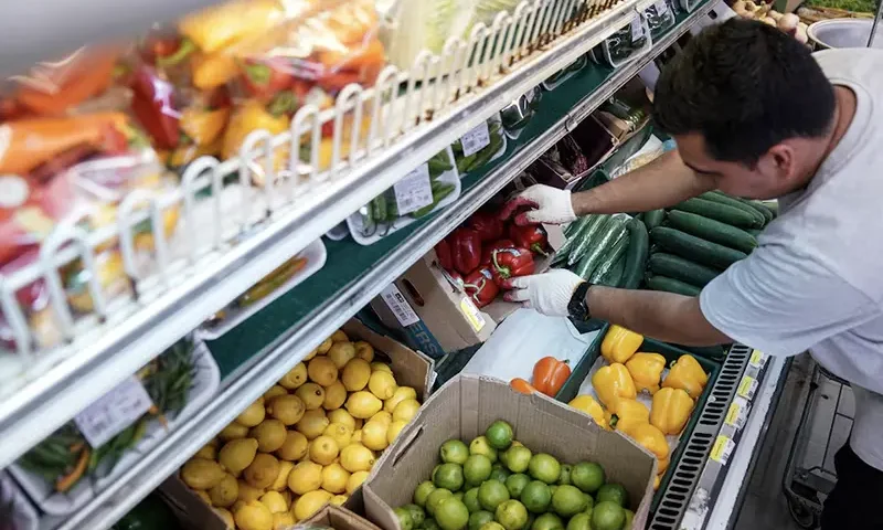 A man arranges produce at Best World Supermarket in the Mount Pleasant neighborhood of Washington, D.C., U.S., August 19, 2022. REUTERS/Sarah Silbiger/File Photo