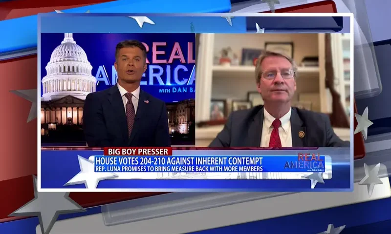 Video still from Real America on One America News Network showing a split screen of the host on the left side, and on the right side is the guest, Rep. Tim Burchett.