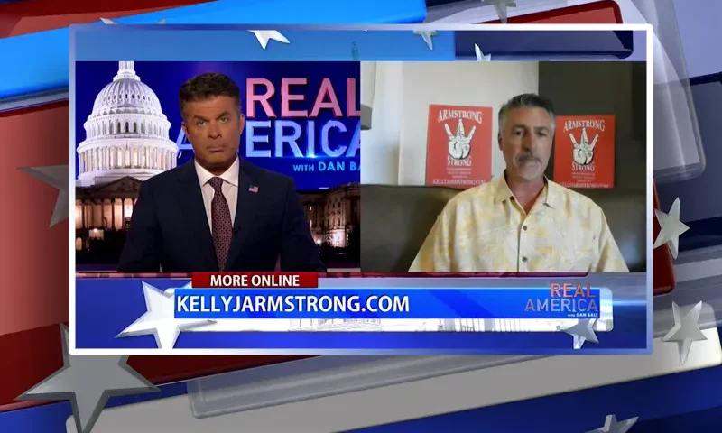 Video still from Real America on One America News Network showing a split screen of the host on the left side, and on the right side is the guest, Kelly Armstrong.