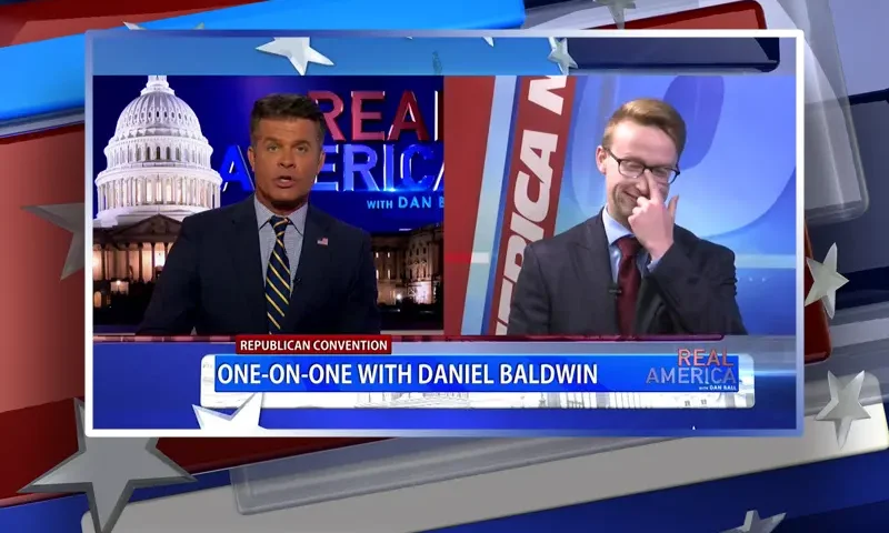 Video still from Real America on One America News Network showing a split screen of the host on the left side, and on the right side is the guest, Daniel Baldwin.