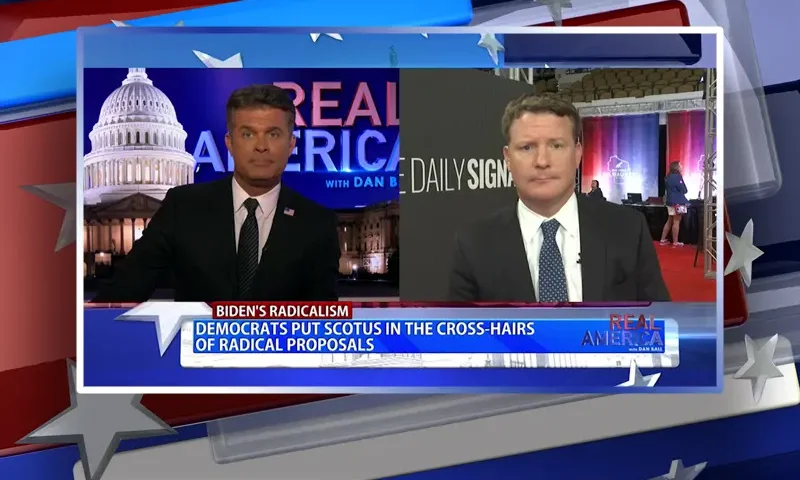 Video still from Real America on One America News Network showing a split screen of the host on the left side, and on the right side is the guest, Mike Davis.