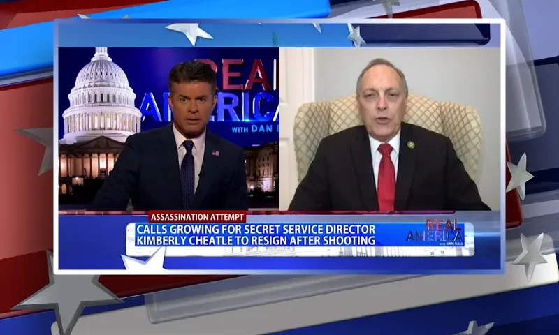 Video still from Real America on One America News Network showing a split screen of the host on the left side, and on the right side is the guest, Rep. Andy Biggs.