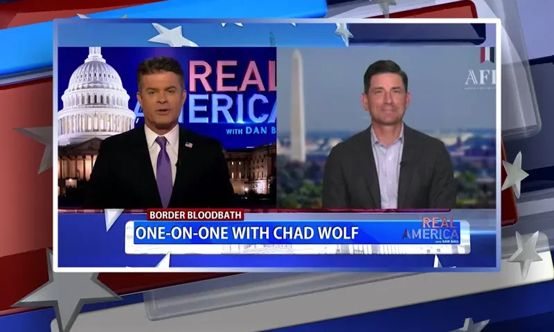 Video still from Real America on One America News Network showing a split screen of the host on the left side, and on the right side is the guest, Chad Wolf.