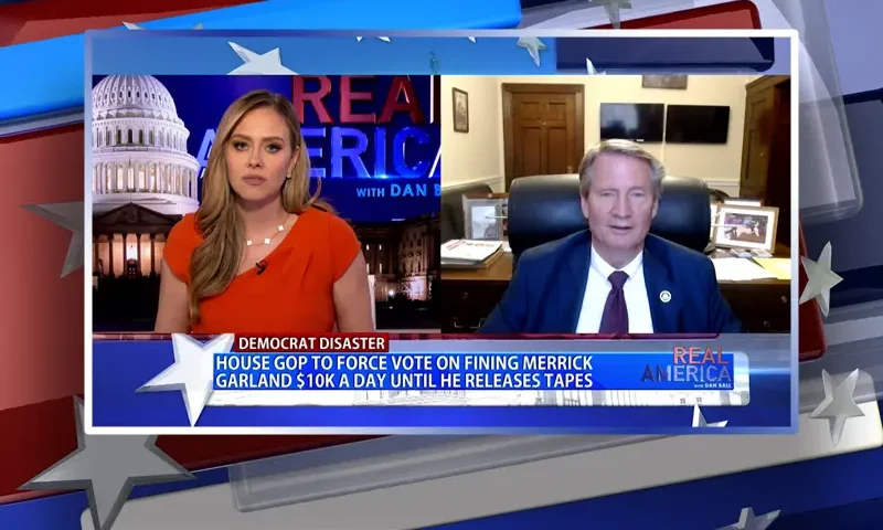 Video still from Real America on One America News Network showing a split screen of the host on the left side, and on the right side is the guest, Tim Burchett.