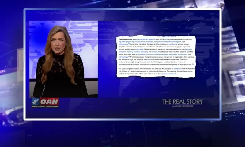 Video still of the host of The Real Story at the desk of their talk show on One America News Network.