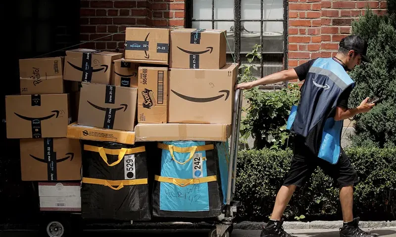 An Amazon delivery worker pulls a delivery cart full of packages during its annual Prime Day promotion in New York City, U.S., June 21, 2021. REUTERS/Brendan McDermid/File Photo