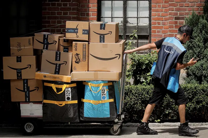 An Amazon delivery worker pulls a delivery cart full of packages during its annual Prime Day promotion in New York City, U.S., June 21, 2021. REUTERS/Brendan McDermid/File Photo